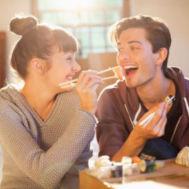 A woman feeding her boyfriend with chopsticks